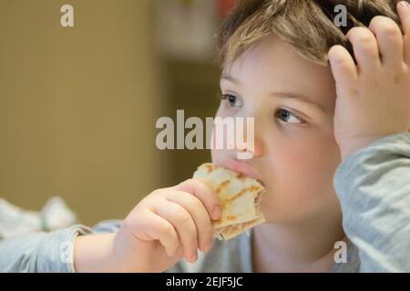 Boy Eating Piadina While Watching TV at Home Stock Photo