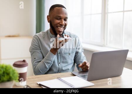 African Businessman With Smartphone Using Voice Assistant App In Office Stock Photo