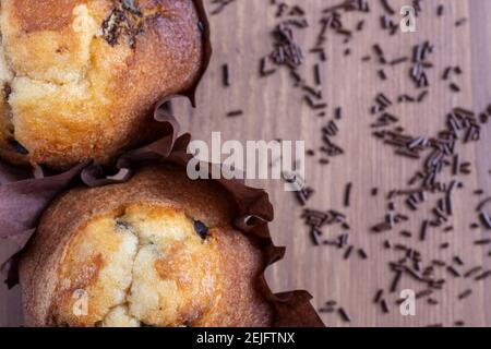 Aerial view of two chocolate muffins, on wooden table with chocolate shavings, out of focus, horizontal, with copy space Stock Photo