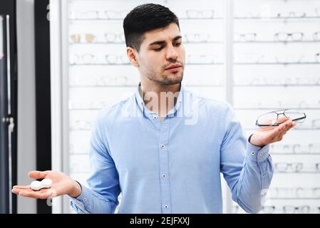 Thinking guy choosing between eyeglasses and contacts Stock Photo