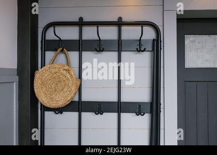 A wicker bag hangs on a hanger near the front door in the interior of a Scandinavian house Stock Photo