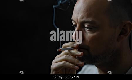 Close up of a man smoking a cigarette. Isolated on black background. Stock Photo