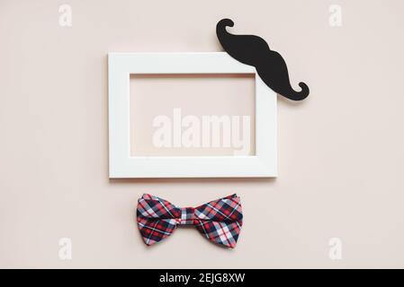 Happy Father's Day.White frame with bow tie and false mustache on a beige background Stock Photo