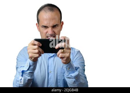 Mature man in formal wear playing on his smartphone and gritting his teeth. Stock Photo