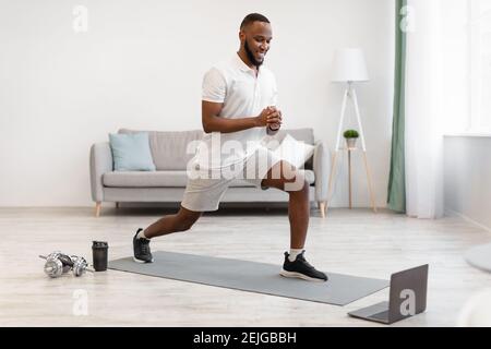 African American Guy Doing Forward Lunge Exercise Training At Home Stock Photo