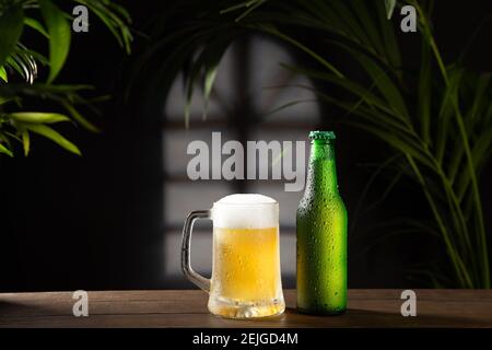 Beer mug and bottle on dark background on wooden base. Stock Photo