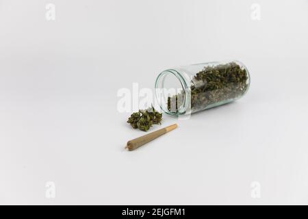 Glass jar full of marijuana buds, dried marijuana flowers and a marijuana cigarette. Isolated on white background. Sweet addiction Stock Photo