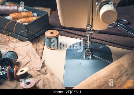 Sewing workplace with sewing machine and thread. Side view, close-up. Stock Photo
