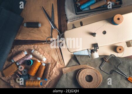 Sewing accessories and sewing machine on vintage background. Top view with blurred foreground. The concept of sewing. Stock Photo