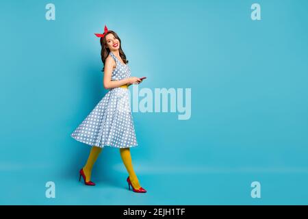 Full length body size profile side view of nice attractive lovely pretty glamorous cheerful wavy-haired girl walking using cell free time, isolated on Stock Photo
