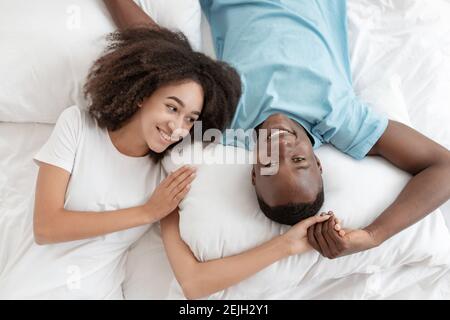 Young family lying in bed together, romantic couple of lovers are looking at each other Stock Photo