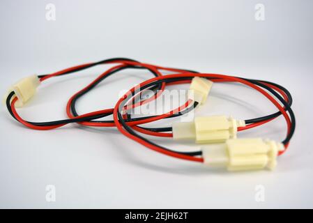 Large electric red black wires on 12V, 220V with white plastic dad connector and mom located on a white plastic background. Stock Photo