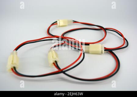 Large electric red black wires on 12V, 220V with white plastic dad connector and mom located on a white plastic background. Stock Photo