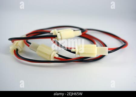 Large electric red black wires on 12V, 220V with white plastic dad connector and mom located on a white plastic background. Stock Photo