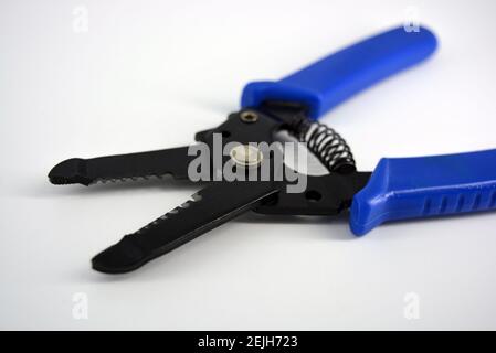 Metal plassentes with blue plastics handles for trimming wires of different diameter located on a white plastic background. Stock Photo