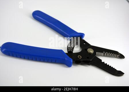 Metal plassentes with blue plastics handles for trimming wires of different diameter located on a white plastic background. Stock Photo