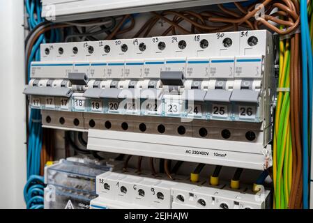 Single-phase fuses in the OFF and ON position and three-phase fuses in the OFF position, placed in the home fuse box, visible electric wires. Stock Photo