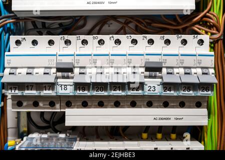 Single-phase fuses in the OFF and ON position and three-phase fuses in the OFF position, placed in the home fuse box, visible electric wires. Stock Photo