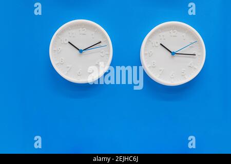 Simple modern wall clocks in white color frame, isolated on blue background.House Interior .big round clock hanging on a wall. copy space, deadline Stock Photo