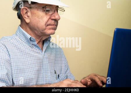 Civil engineer wearing a helmet and working on a laptop Stock Photo