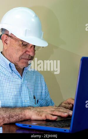 Civil engineer wearing a helmet and working on a laptop Stock Photo