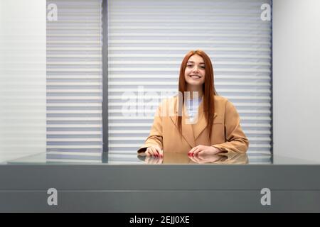 Positive girl stands at the reception in the office