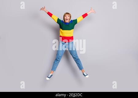 Full length body size photo of happy girl jumping like star careless wearing sweater isolated on pastel grey color background Stock Photo