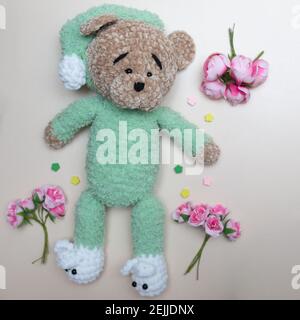 Handmade knitted toy. Knitted bear and flowers on light background. Stock Photo