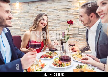 Friends enjoying atmosphere, food, and drink in fancy restaurant Stock Photo