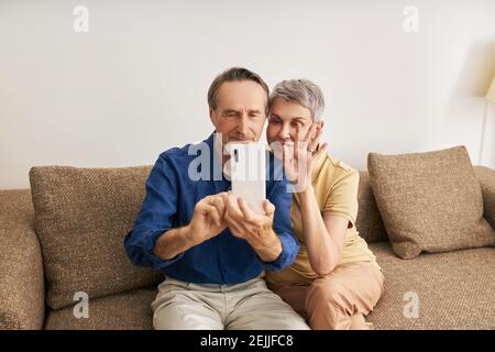 Senior couple making video call while sitting on a sofa Stock Photo