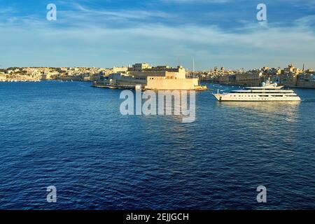 Ancient Valletta in evening colors. View from the walls of the harbor fortification on the departing ocean liner. Postcard. Holidays in Malta. Stock Photo