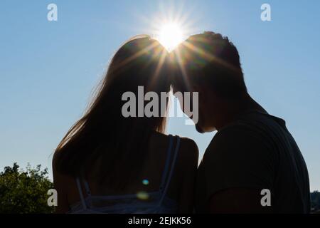 Silhouette of dreaming couple against deep blue sky with sunbeams. Low angle view, concept. Stock Photo