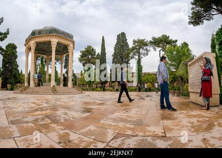 Shiraz, Iran - 04.14.2019: People walking in persian garden with a stone gazebo. Tomb of Hafez Shirazi, famous persian poet. Stock Photo