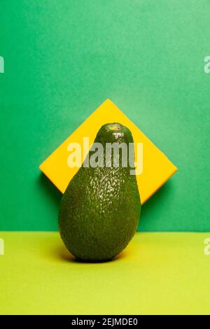 Whole ripe green avocado against two color background Stock Photo