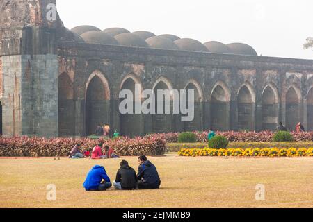 Malda, West Bengal, India - January 2018: Tourists sitting in the gardens of the ancient Adina Masjid mosque in the village of Pandua. Stock Photo