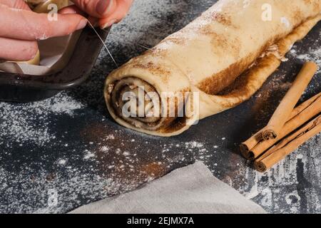 Woman prepare sweet buns and cutting rolls with cinnamon for baking Stock Photo