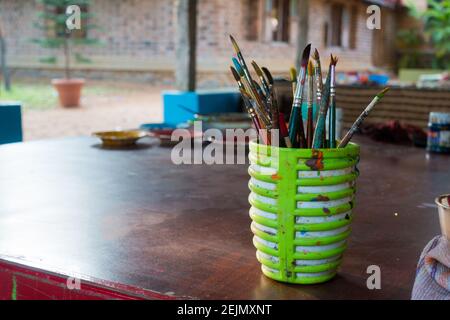A cup full of dirty painting brush with paint stains on the cup outer wall Stock Photo