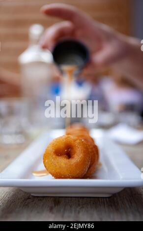 Sweet mini donuts on a white tray with maple syrup and loads of sugar Stock Photo