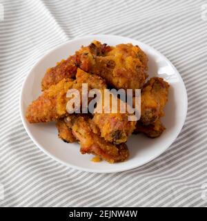 Homemade Spicy Mango Chicken Wings on a white plate on cloth, low angle view. Stock Photo
