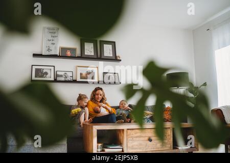 Wide view of cozy living room with plants of mom and children on sofa Stock Photo