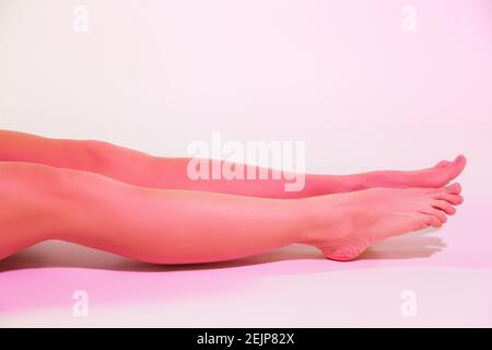 Barefoot slim woman sitting on floor in white studio Stock Photo