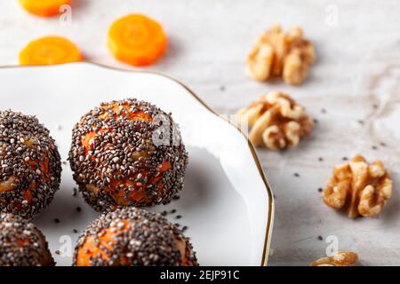 Angled view of kitchen countertop with a flat porcelain plate. Homemade fresh carrot bliss balls (mixture of cookie crumbles, walnut and carrot puree) Stock Photo