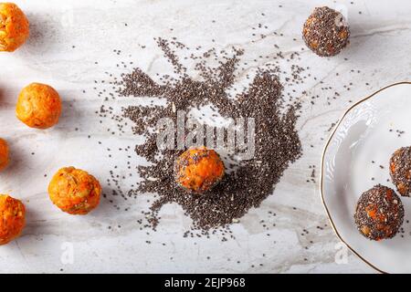 Close up top view image of  preparation of homemade carrot cake bliss balls. Hand rolled carrot, cookie crumble and walnut mixture is dipped into a pi Stock Photo