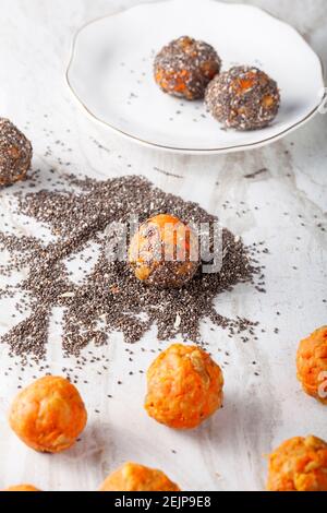 Close up top view image of  preparation of homemade carrot cake bliss balls. Hand rolled carrot, cookie crumble and walnut mixture is dipped into a pi Stock Photo