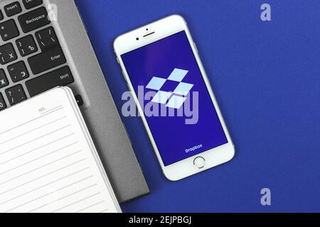 Kharkov, Ukraine - February 22, 2021: Dropbox application on Apple smartphone screen, flat lay and blue background, copy space and banner with logo, p Stock Photo