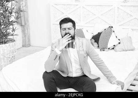 Tired of waiting. Elegant man yawn sitting on bed. Bearded man in classy style. Fashion look of groom. Wedding man. Formal wear for gentleman. Fashion and style. Best man. Stock Photo