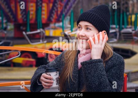 Girl with coffee in cold weather talking on the phone in the park Stock Photo