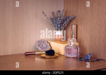 Beauty products with jewelry by flower vase of lavanda