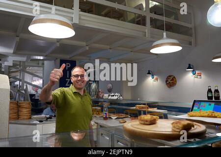 MAY 19, 2017 - FLORENCE, ITALY: Friendly worker at pizzeria smiling and giving thumbs up to the camera in Florence, a few streets from the Duomo. Stock Photo