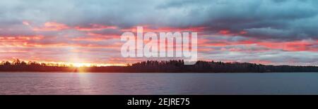 Colorful sunset with dramatic clouds on the lake. Panoramic landscape. Stock Photo